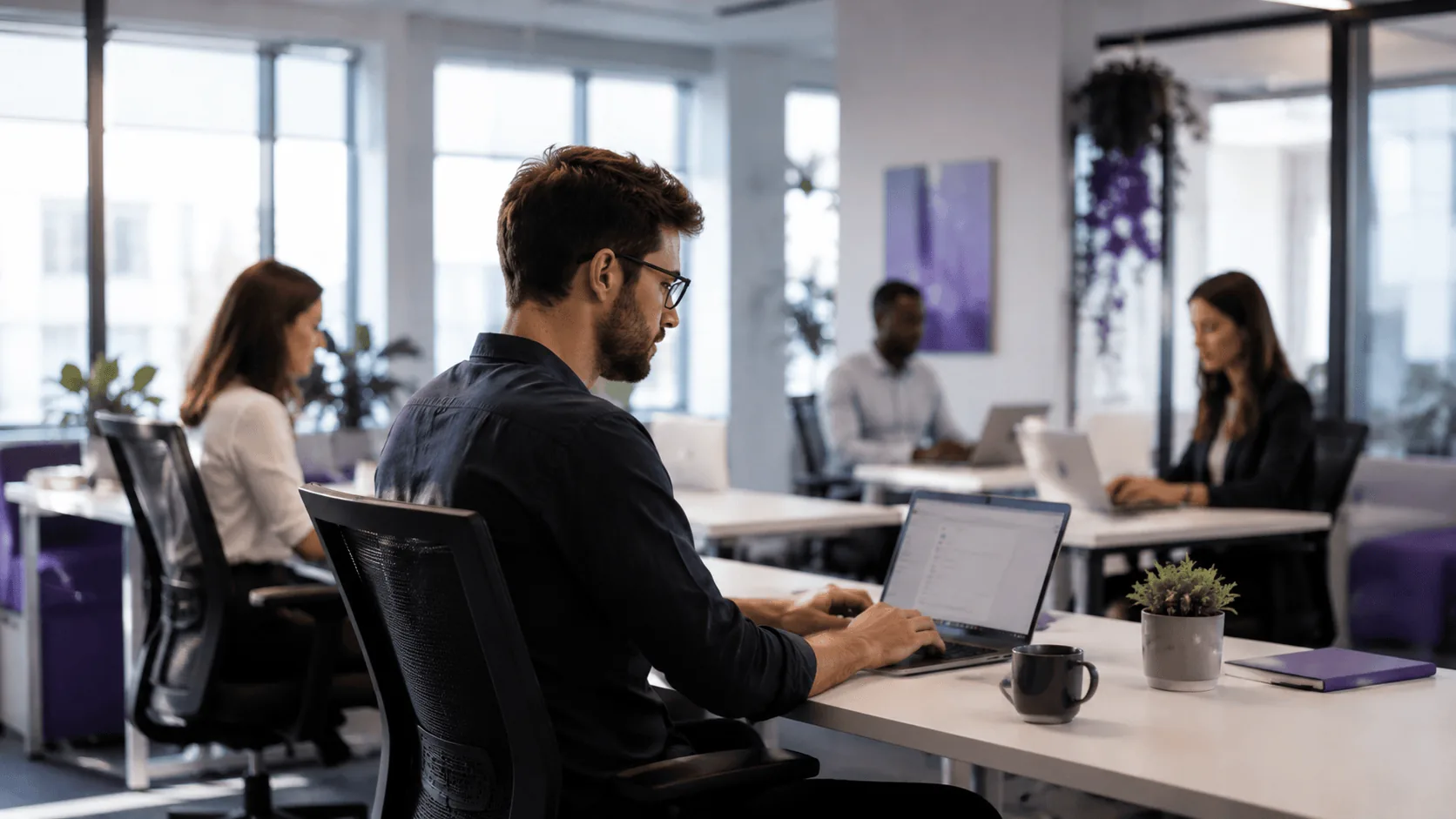 Colleagues working on laptops in an open-space office, preparing business AI assistant use cases.